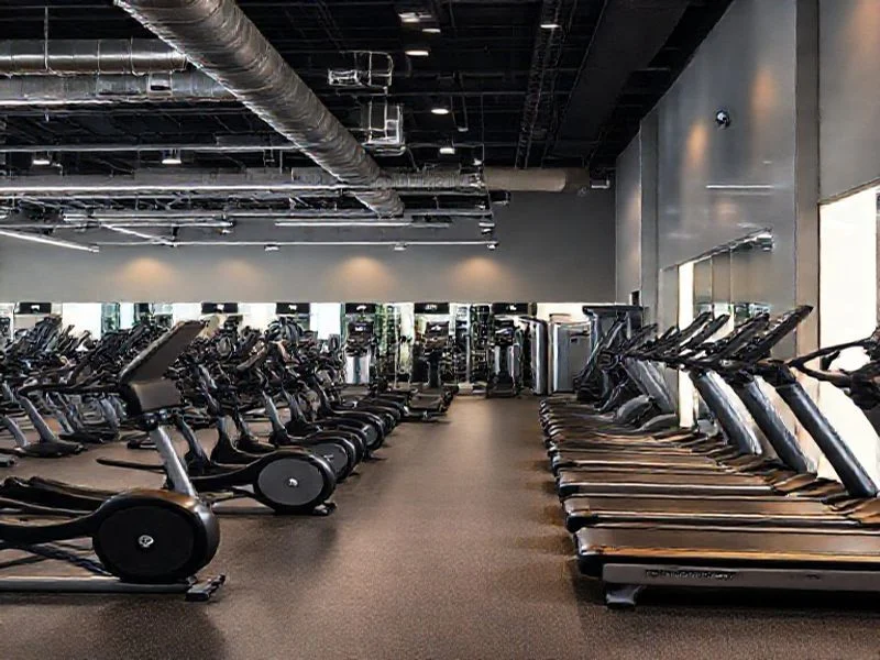 A close-up of a sleek digital display panel embedded in a fitness machine. The screen shows abstract, glowing neural network patterns and data streams, symbolizing AI intelligence. The surrounding machine chassis is a dark, matte finish, making the glowing screen the focal point, suggesting advanced, smart technology.
